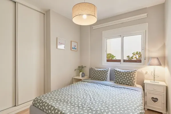 First bedroom with a double bed, wardrobe and bedside lamps at H&T Dream Stays apartment in Málaga