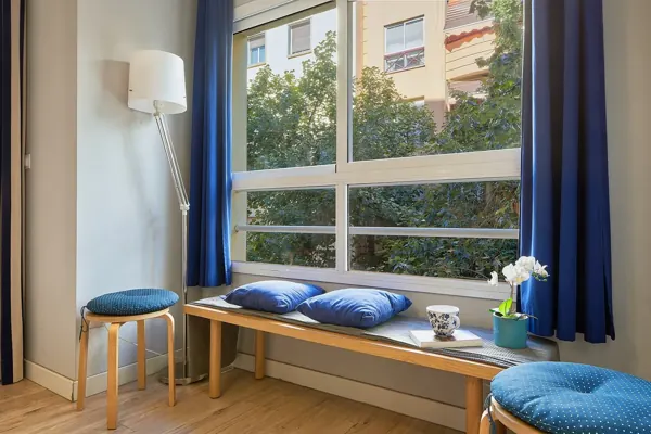 Large living room window with a wooden bench and blue curtains at H&T Dream Stays apartment in Málaga