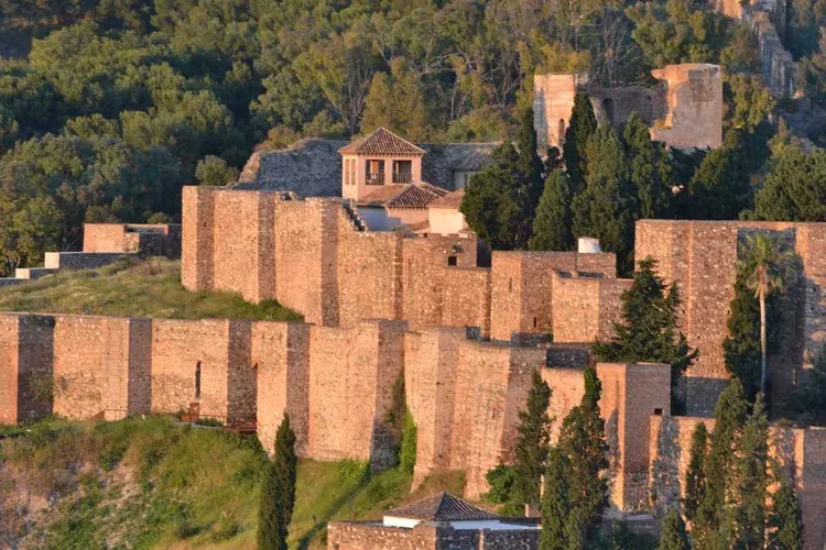 Stone walls and towers of Gibralfaro Castle surrounded by trees in Málaga