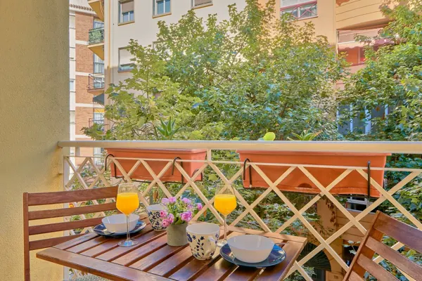 Balcony with a wooden table overlooking trees at H&T Dream Stays apartment in Málaga