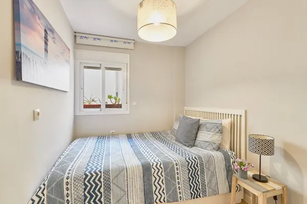 Second bedroom with patterned bedding, wall art and a window at H&T Dream Stays apartment in Málaga