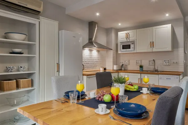 Kitchen cabinets and dining table set for a meal at H&T Dream Stays apartment in Málaga